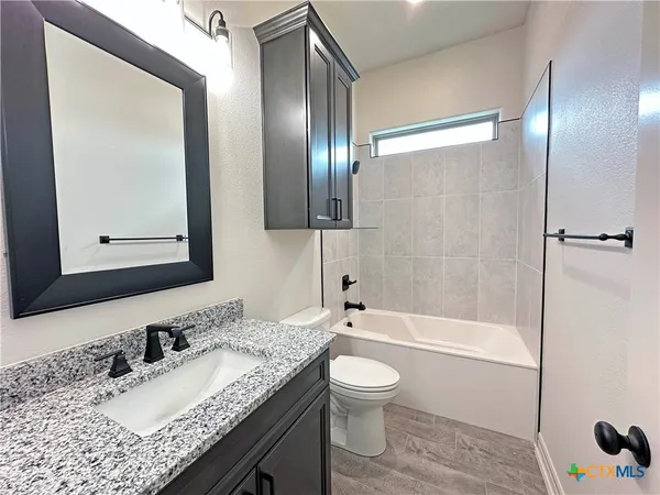 a bathroom with a granite countertop sink toilet and shower