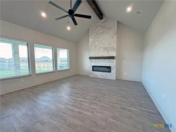 an empty room with windows and fireplace