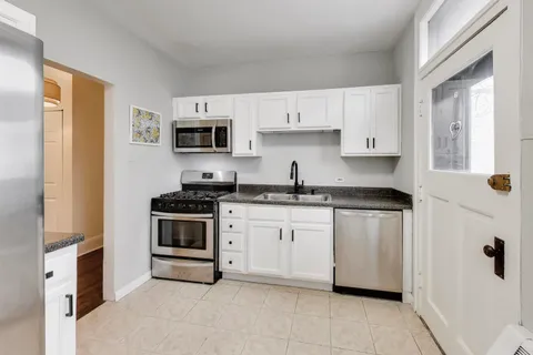 a kitchen with granite countertop white cabinets and stainless steel appliances