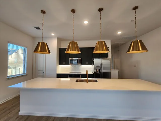 a living room with kitchen island granite countertop wooden floor and stainless steel appliances