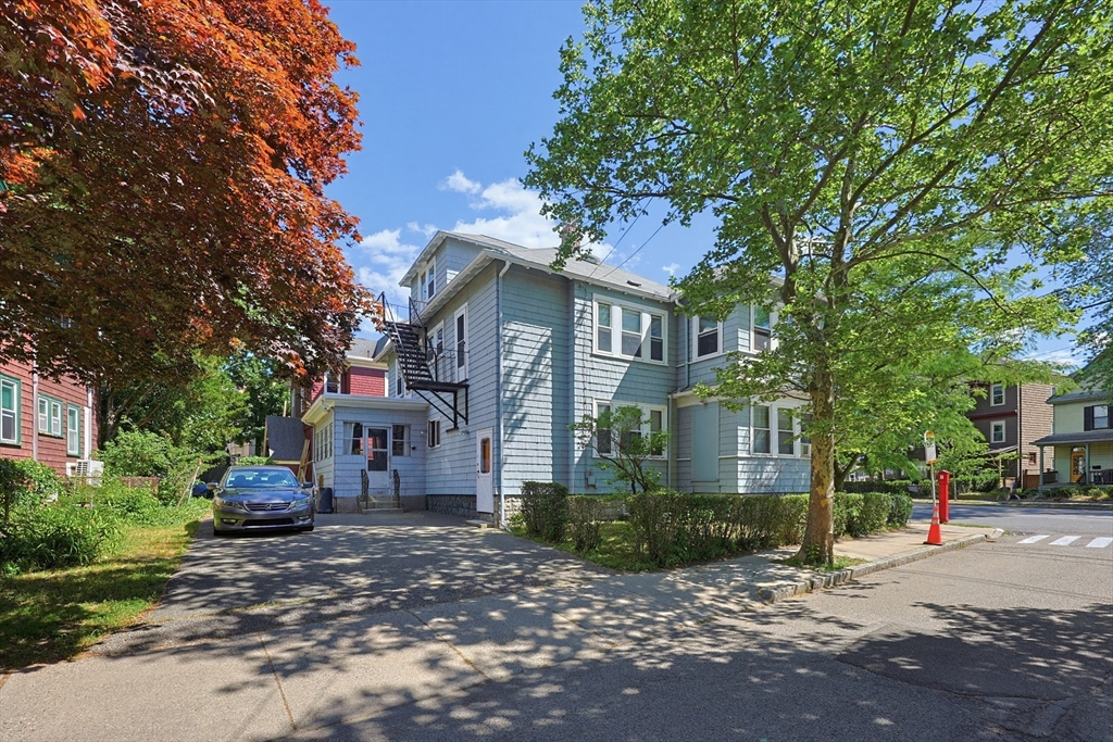 157 Elm Street Somerville, MA 02144 - Photo 18 of 19 a front view of a house with a garden and tree