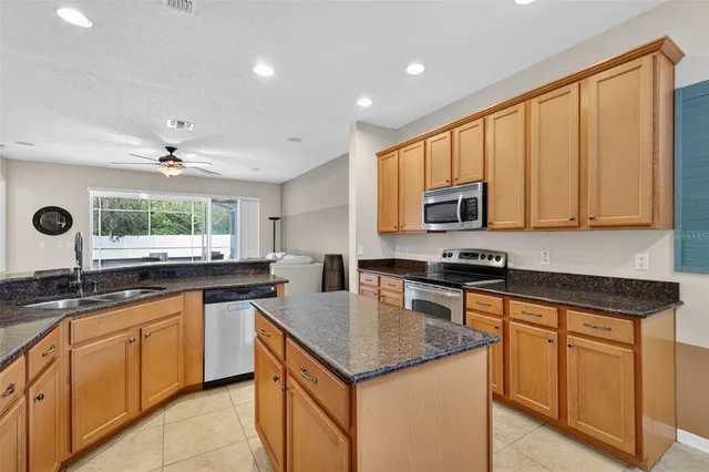 a kitchen with granite countertop stainless steel appliances sink stove microwave and cabinets