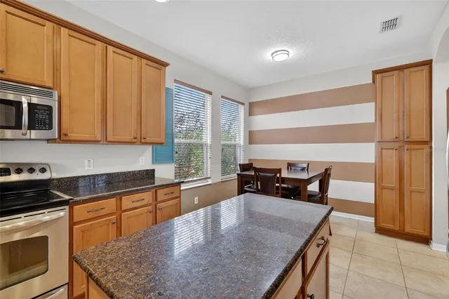 a kitchen with granite countertop a stove a oven a dining table and chairs