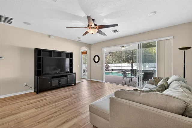 a living room with furniture a flat screen tv and a floor to ceiling window