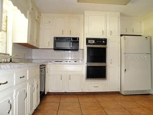 a white kitchen with granite countertop white cabinets and stainless steel appliances