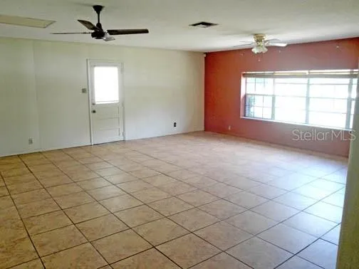 an empty room with windows and fan