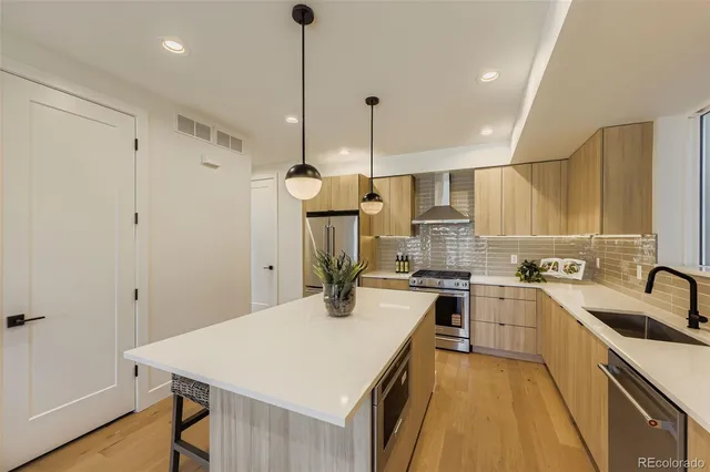 a kitchen with a stove a sink a kitchen island with wooden floor and cabinets