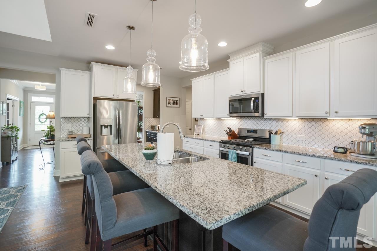 3373 Willow Green Drive Apex, NC 27502 - Photo 6 of 42 a kitchen with stainless steel appliances granite countertop a stove refrigerator a oven a sink a dining table and chairs with wooden floor