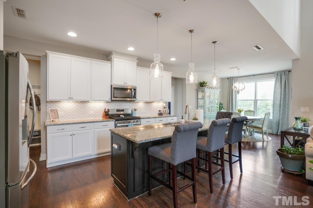 3373 Willow Green Drive Apex, NC 27502 - Photo 7 of 42 a kitchen with a dining table chairs stainless steel appliances and cabinets
