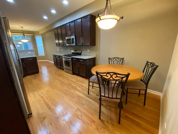 a kitchen with stainless steel appliances wooden floor dining table and chairs