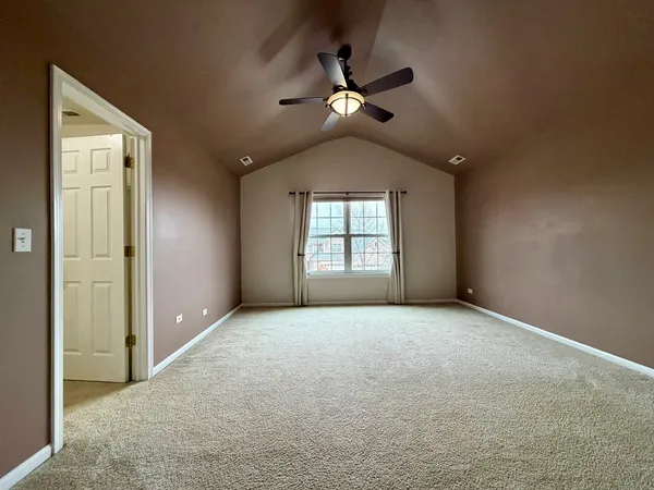 an empty room with chandelier fan and windows