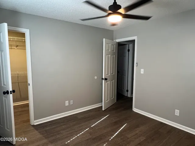 an empty room with closet and a ceiling fan