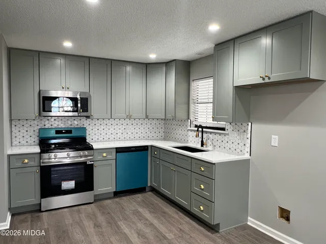 a kitchen with stainless steel appliances granite countertop a sink stove and cabinets