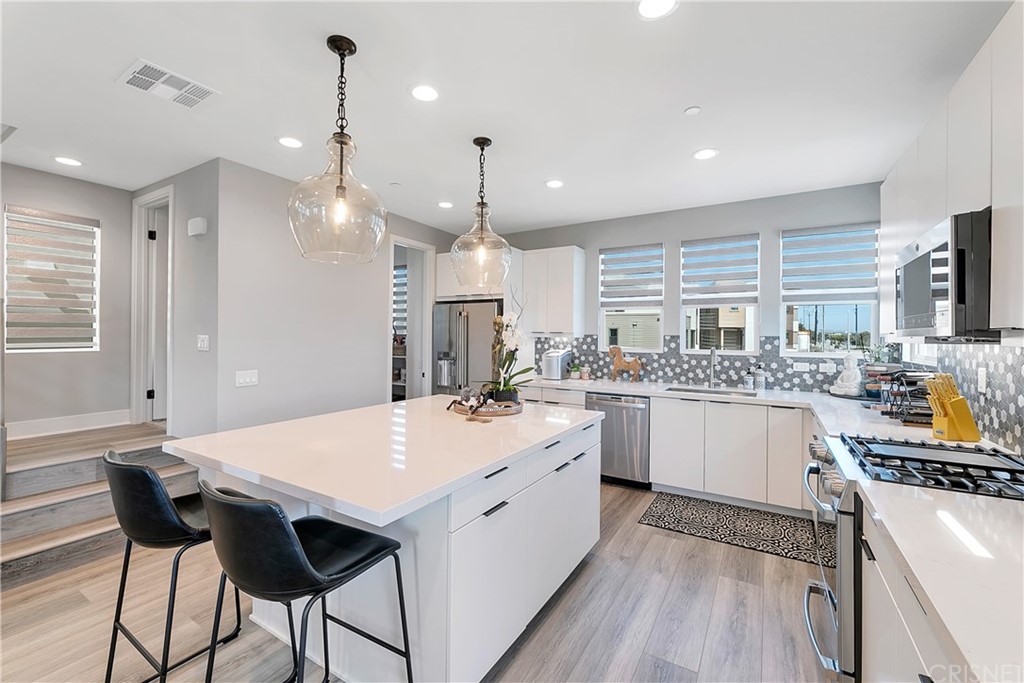 1051 Canal Street Oxnard, CA 93035 - Photo 15 of 37 a kitchen with a stove a sink a kitchen island with chairs and wooden floor