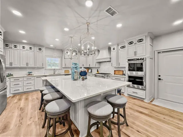 a kitchen with stainless steel appliances kitchen island granite countertop a table chairs sink and cabinets