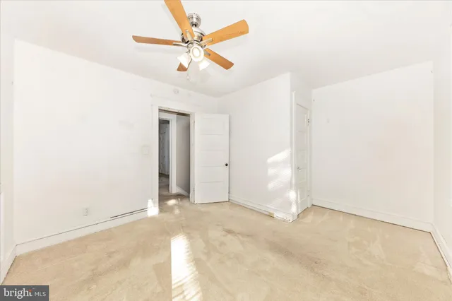 an empty room with closet and a ceiling fan