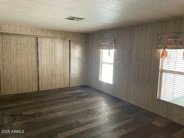 an empty room with wooden floor and windows with curtains