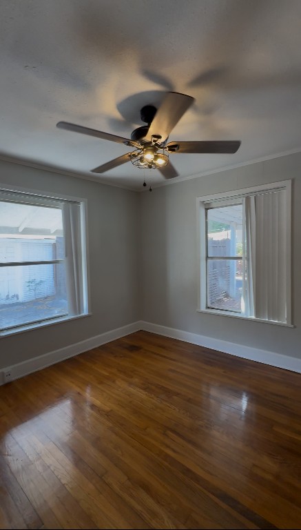 1 East 53rd Street Austin, TX 78751 - Photo 11 of 13 Spare room featuring plenty of natural light, dark wood-style flooring, a ceiling fan, and crown molding