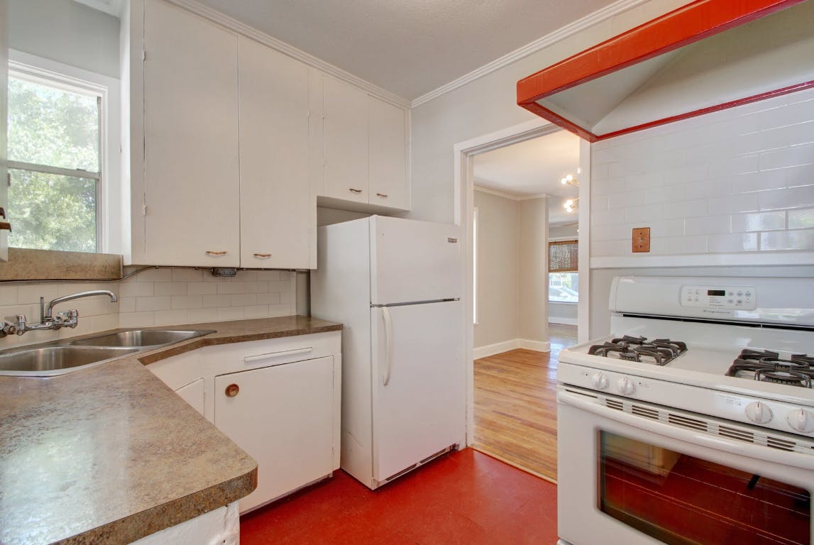 1 East 53rd Street Austin, TX 78751 - Photo 7 of 13 Kitchen with ornamental molding, white appliances, white cabinets, tasteful backsplash, and dark floors