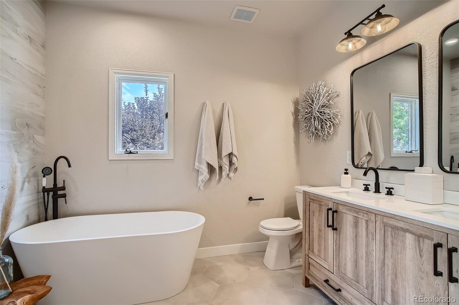 3806 Simms Court Wheat Ridge, CO 80033 - Photo 13 of 30 a bathroom with a white tub a toilet a sink and mirror