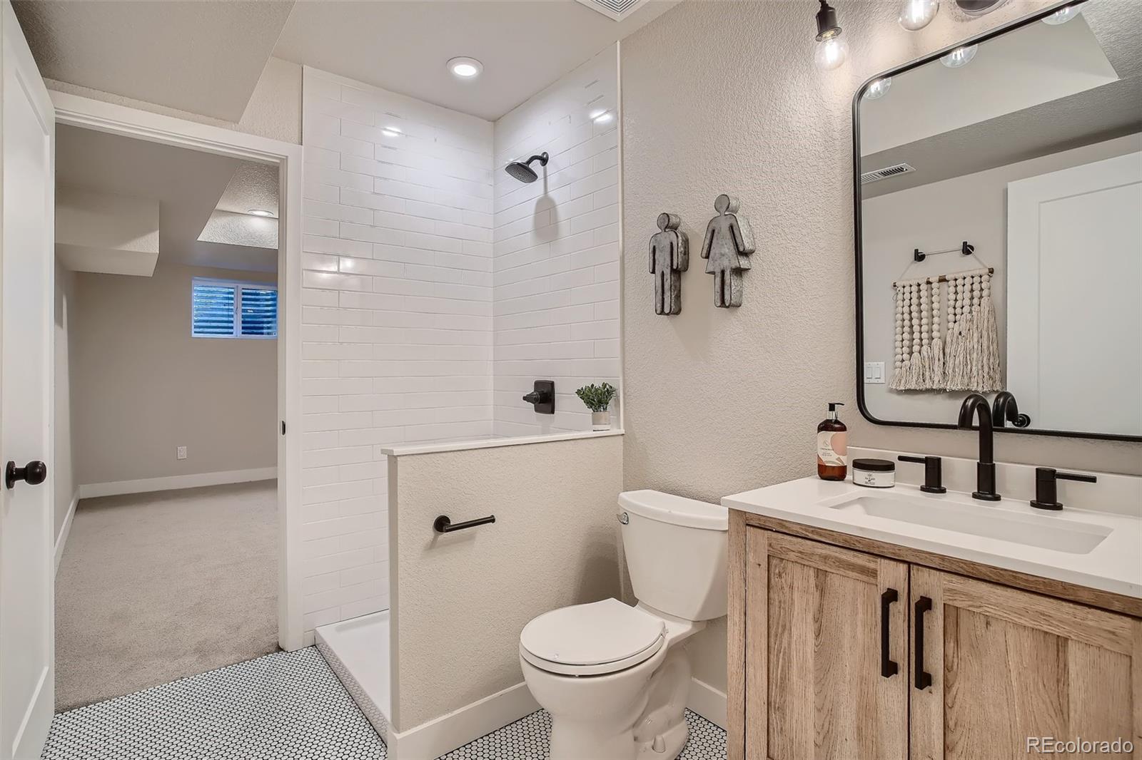 3806 Simms Court Wheat Ridge, CO 80033 - Photo 22 of 30 a bathroom with a sink a toilet a mirror and shower