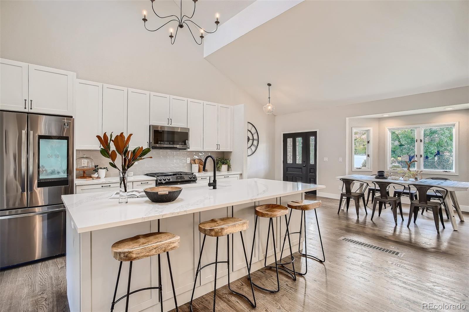 3806 Simms Court Wheat Ridge, CO 80033 - Photo 8 of 30 a kitchen with stainless steel appliances a dining table chairs stove refrigerator and microwave