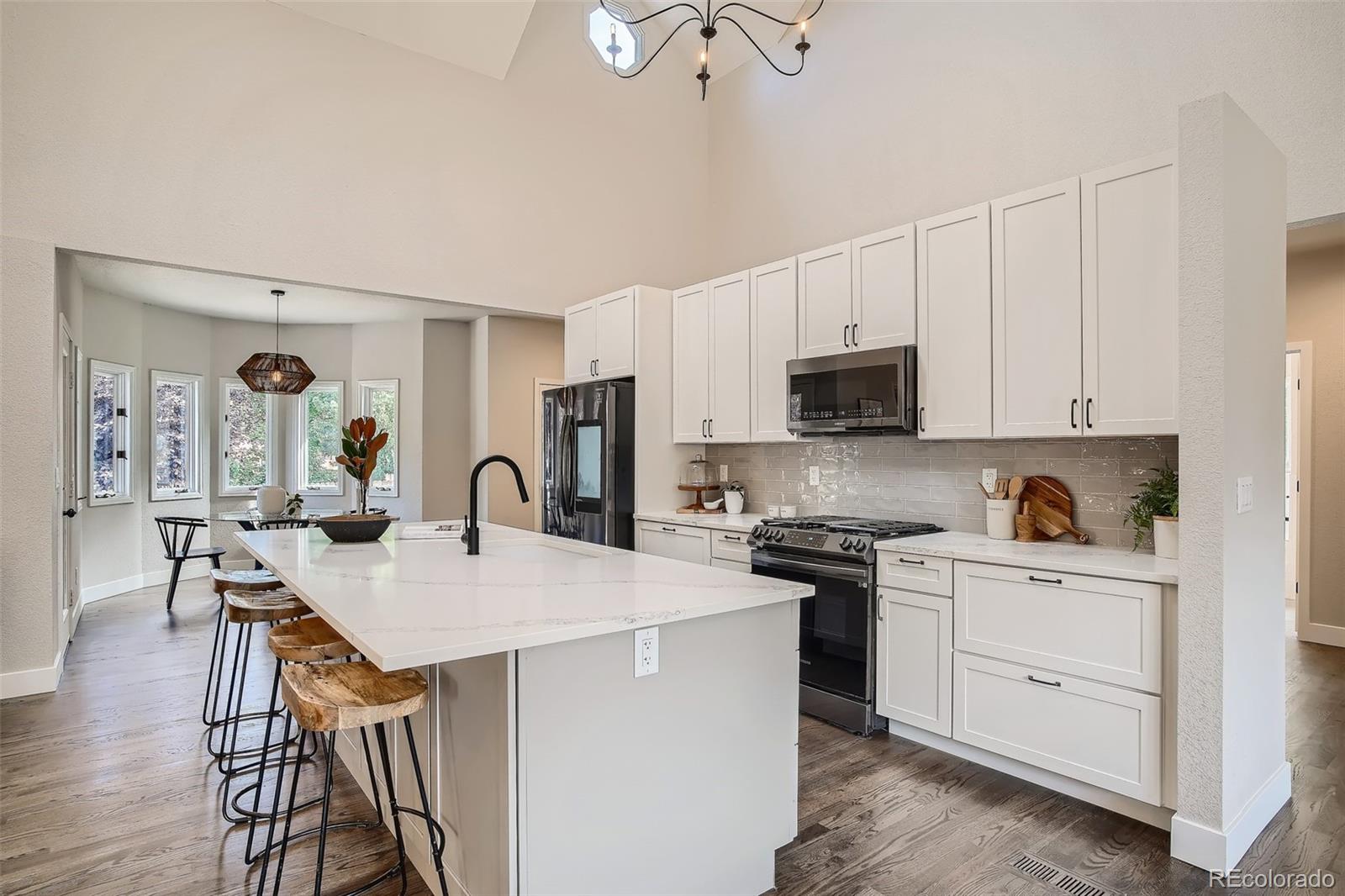 3806 Simms Court Wheat Ridge, CO 80033 - Photo 9 of 30 a open kitchen with stainless steel appliances granite countertop a stove top oven a sink dishwasher and white cabinets with wooden floor