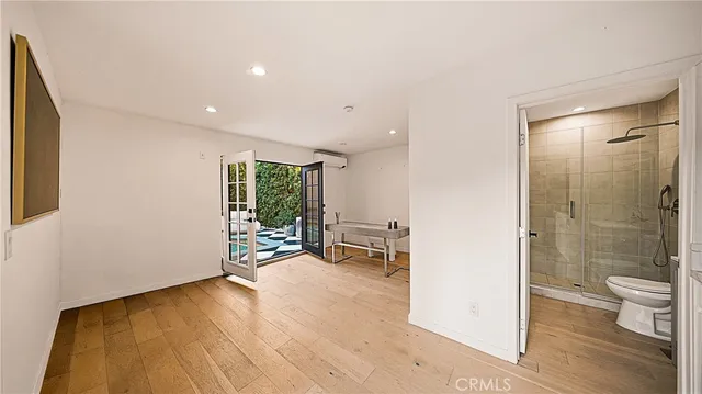 a view of a hallway with wooden floor and a bathroom