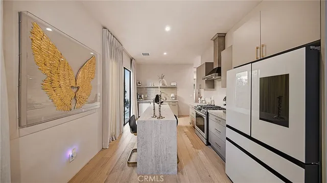 a kitchen with stainless steel appliances a refrigerator a stove top oven and wooden floor