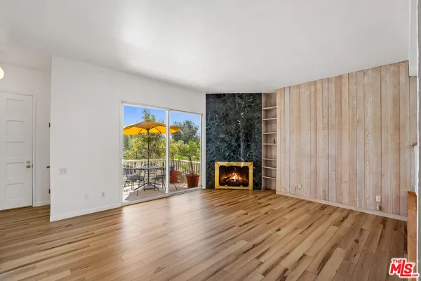 an empty room with windows fireplace and wooden floor