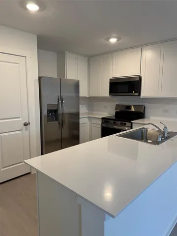 a kitchen with refrigerator a microwave a sink and cabinets