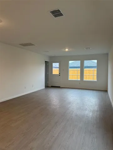 a view of an empty room with a window and wooden floor