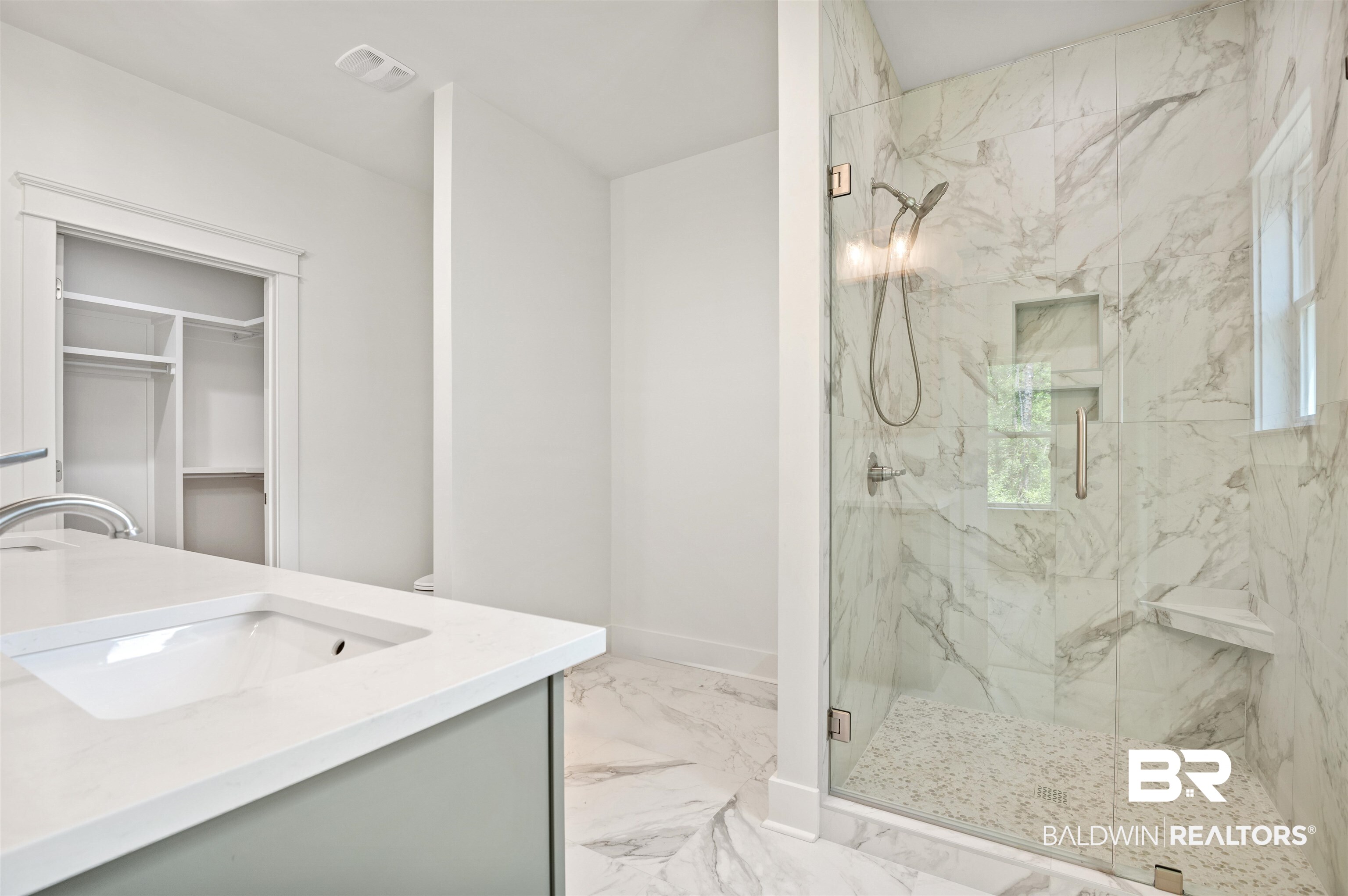 657 Island Way Gulf Shores, AL 36542 - Photo 17 of 59 Bathroom with marble finish floors, a marble finish shower, vanity, a walk in closet, and baseboards