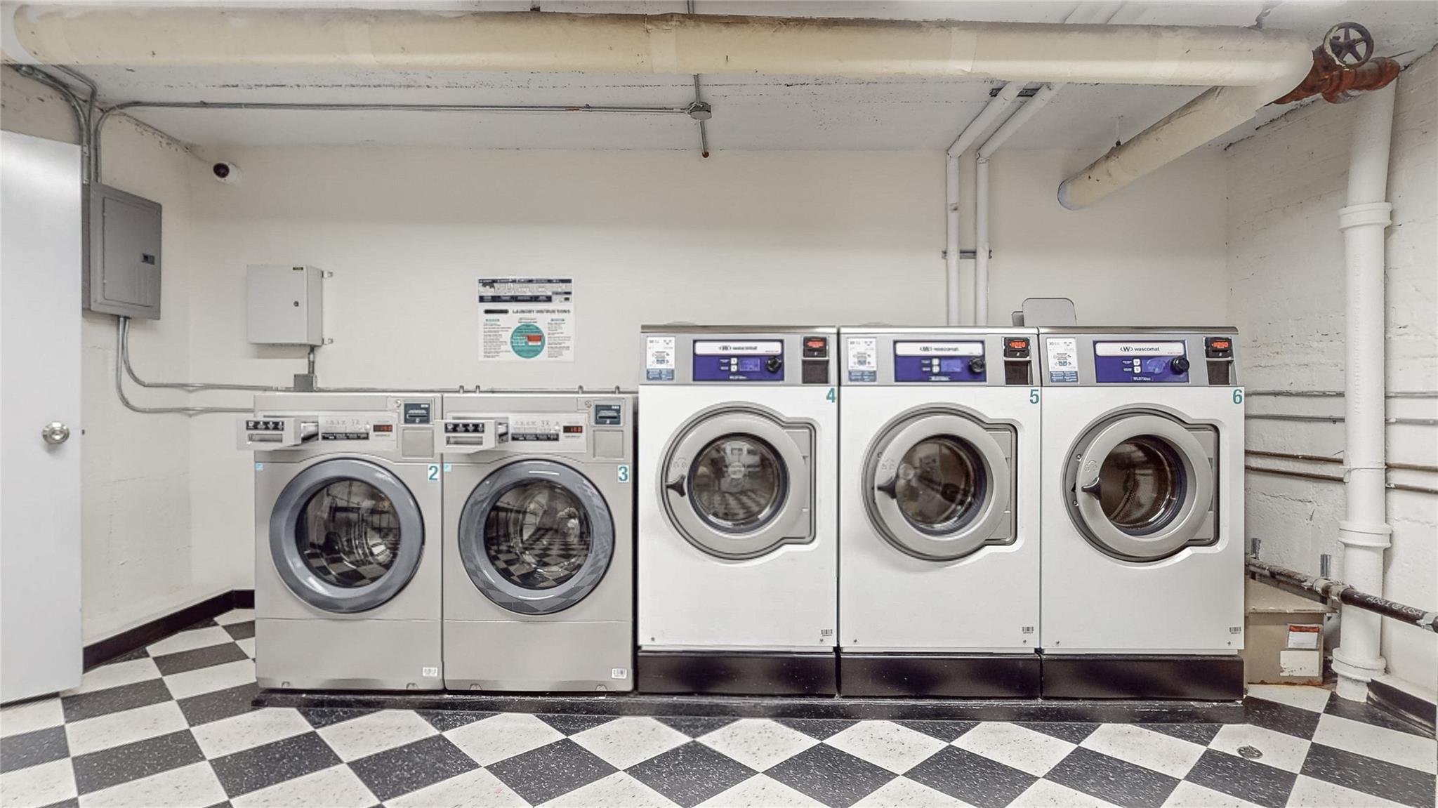 83-10 35th Avenue, Unit 3O Queens, NY 11372 - Photo 8 of 10 Community laundry room with dark floors, washing machine and clothes dryer, and electric panel