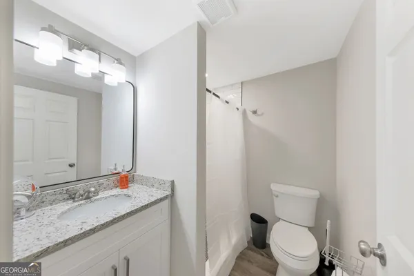 a bathroom with a granite countertop sink a toilet and a mirror