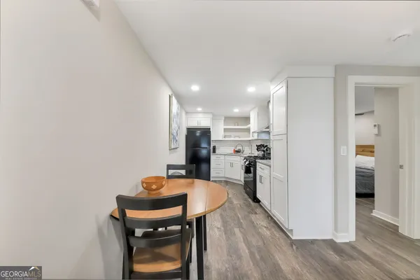 a kitchen with stainless steel appliances granite countertop a refrigerator a sink a stove and white cabinets with wooden floor