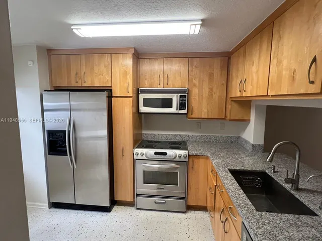 a kitchen with granite countertop a refrigerator stove and microwave