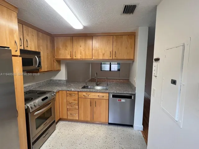 a kitchen with stainless steel appliances granite countertop a stove a sink and a refrigerator