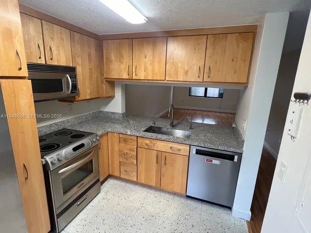a kitchen with granite countertop a stove sink and microwave