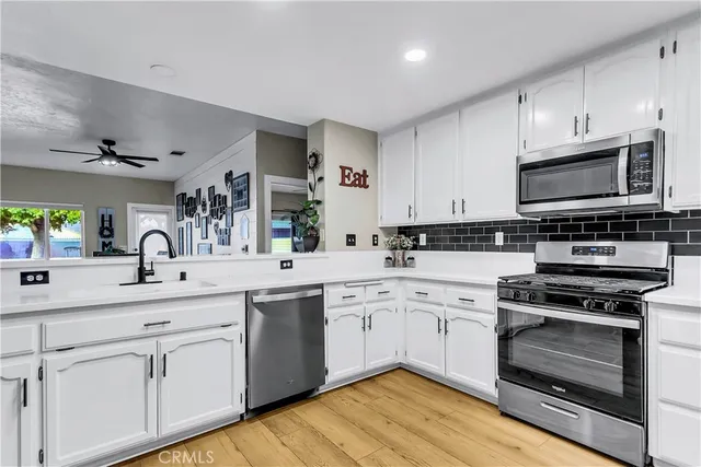a kitchen with stainless steel appliances granite countertop a white stove top oven a sink and white cabinets