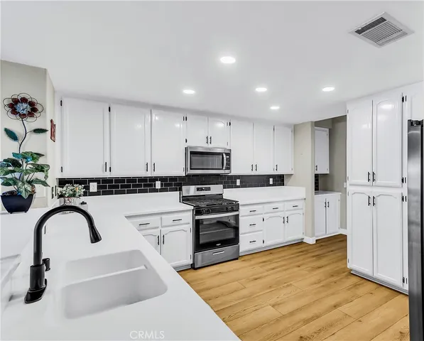 a kitchen with stainless steel appliances granite countertop a refrigerator a stove top oven a sink and dishwasher