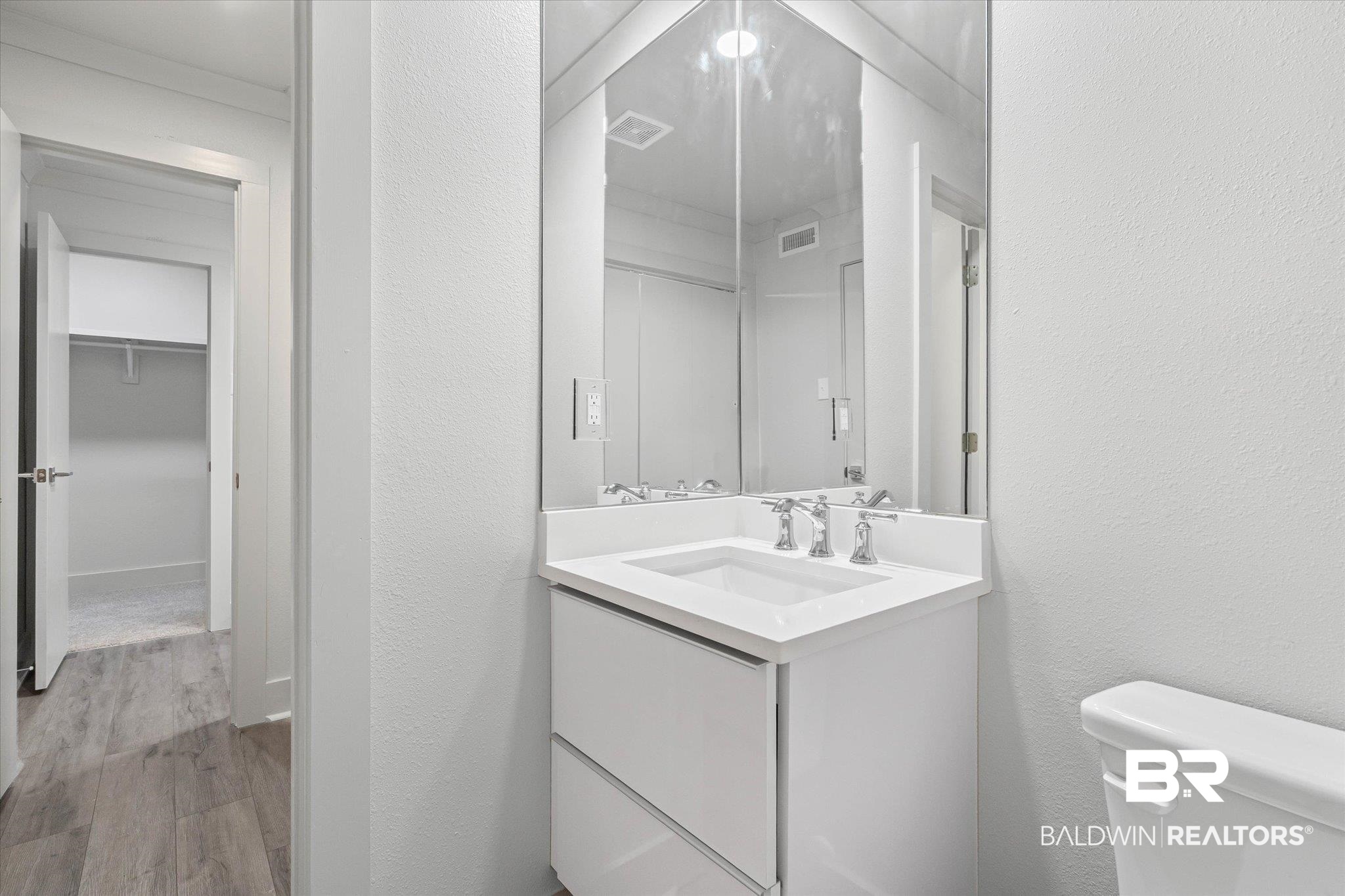 3655 Old Shell Road, Unit 712 Mobile, AL 36608 - Photo 14 of 19 Half bath featuring vanity, light wood finished floors, a textured wall, and a walk in closet