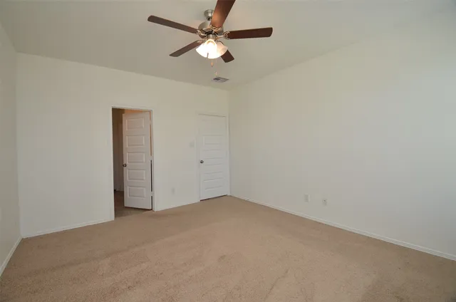 an empty room with a chandelier fan and a ceiling fan