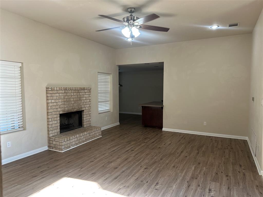 208 Pearl Drive Hewitt, TX 76643 - Photo 3 of 17 Unfurnished living room with a brick fireplace, wood finished floors, and a ceiling fan