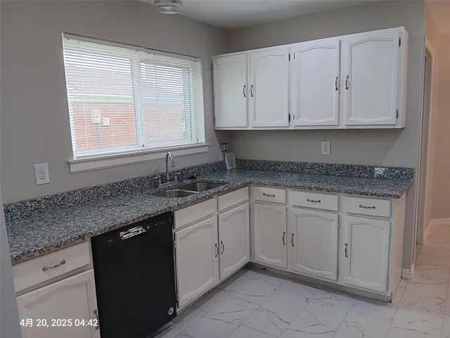 a kitchen with granite countertop white cabinets stainless steel appliances a sink and a window