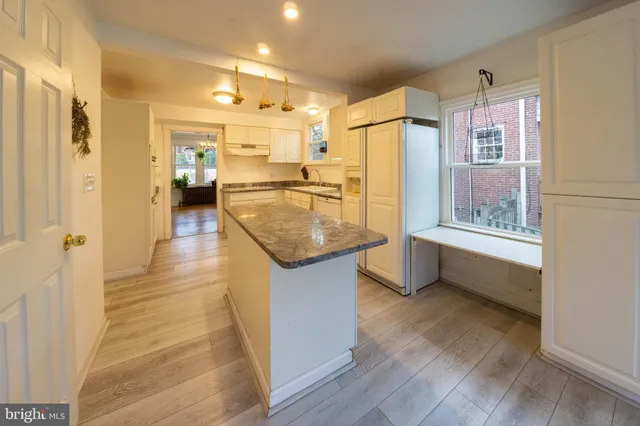 a kitchen with stainless steel appliances granite countertop a refrigerator a sink dishwasher and white cabinets with wooden floor