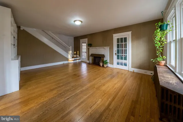 a view of an empty room with wooden floor fireplace and a window