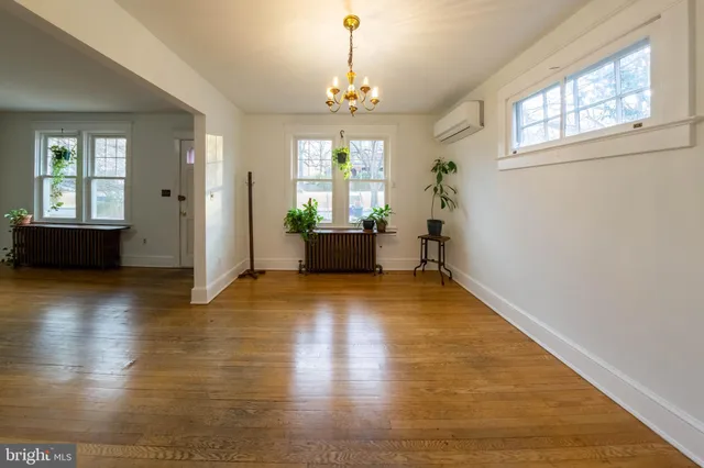 a view of an empty room with wooden floor and windows