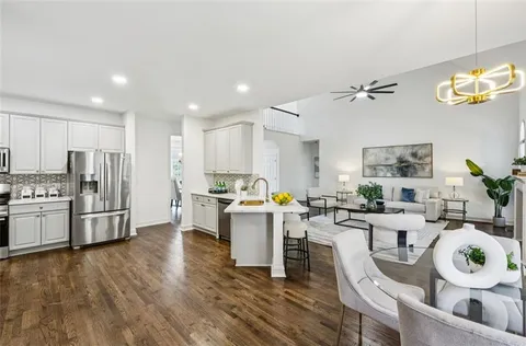 a kitchen with stainless steel appliances a stove a sink a refrigerator white cabinets and wooden floor