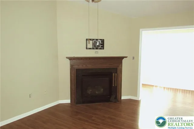 a view of an empty room with wooden floor and a fireplace